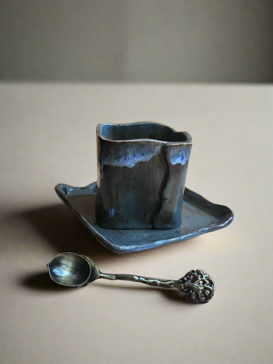 Taza cuadrada de cerámica azul oscuro con plato a juego, vista frontal